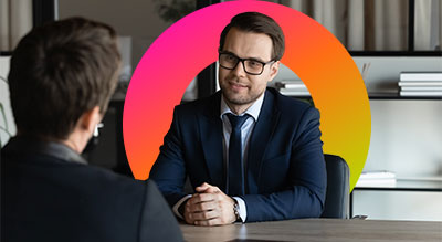 Two people in business suits chatting at a desk 